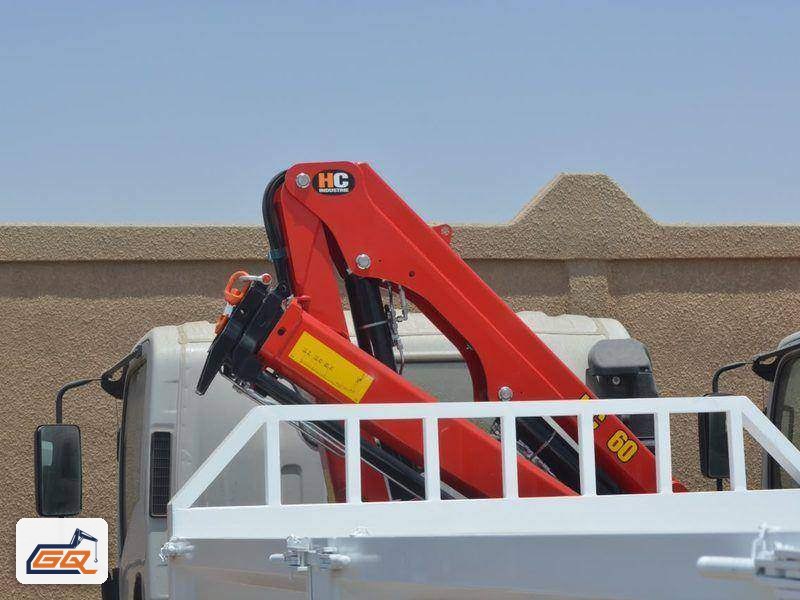 كرين مفصلي أحمر مركّب خلف كابينة الشاحنة مع صندوق حمولة معدني